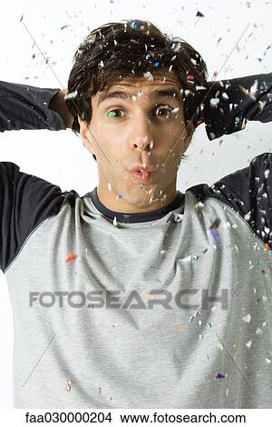 Picture - Man among falling confetti, puckering lips, looking at camera. Fotosearch