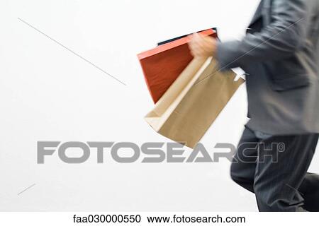 Man running with shopping bags, cropped view View Large Photo Image Stock Image - Man running with shopping bags, cropped view. Fotosearch