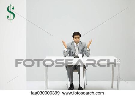 Stock Photo - Man sitting at desk with adding machine, puffed cheeks, hands raised. Fotosearch