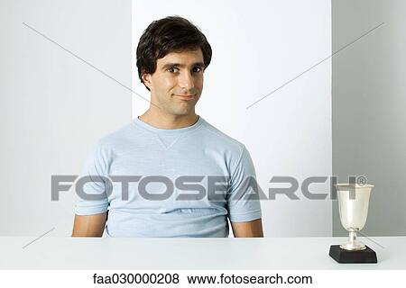 Man sitting next to trophy, smiling at camera View Large Photo Image Stock Photo - Man sitting next to trophy, smiling at camera. Fotosearch