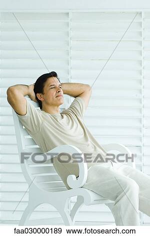 Man sitting on bench, hands behind head, relaxing View Large Photo Image Stock Photo - Man sitting on bench, hands behind head, relaxing. Fotosearch