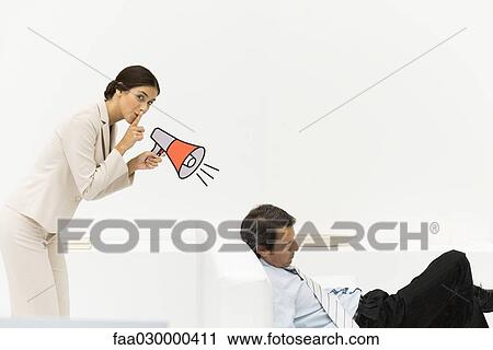 Stock Image - Man sleeping in chair, woman behind him holding megaphone, looking at camera, finger over lips. Fotosearch
