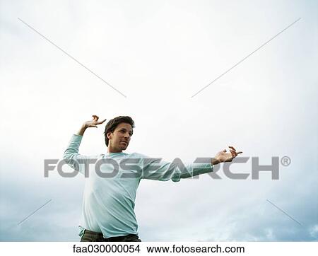 Man standing outdoors, gesticulating, low angle view View Large Photo Image Picture - Man standing outdoors, gesticulating, low angle view. Fotosearch