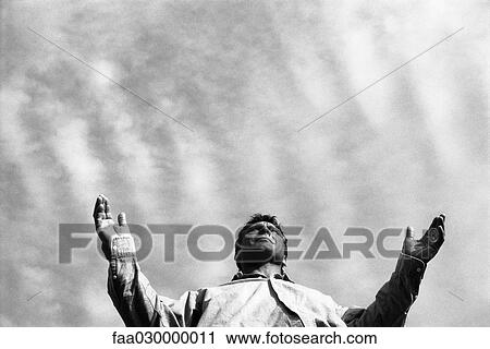 Stock Image - Man standing with arms out, low angle view. Fotosearch