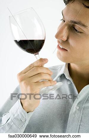 Man studying glass of red wine, close-up View Large Photo Image Stock Photo - Man studying glass of red wine, close-up. Fotosearch