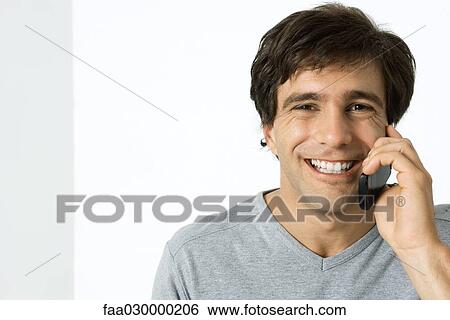 Man using cell phone, smiling at camera View Large Photo Image Stock Photograph - Man using cell phone, smiling at camera. Fotosearch