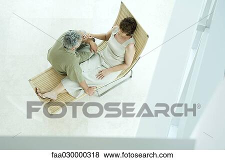 Stock Photo - Mature couple sitting together on lounge chair, high angle view. Fotosearch