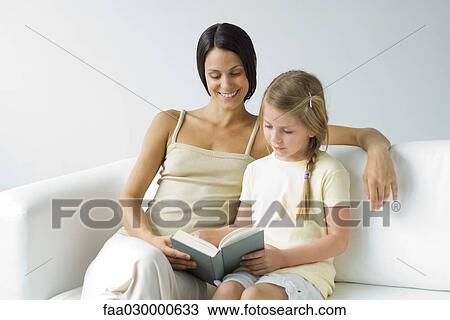 Mother and daughter sitting on sofa, reading book together View Large Photo Image Stock Image - Mother and daughter sitting on sofa, reading book together. Fotosearch