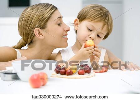 Mother and son preparing food together, boy looking at plum View Large Photo Image Picture - Mother and son preparing food together, boy looking at plum. Fotosearch