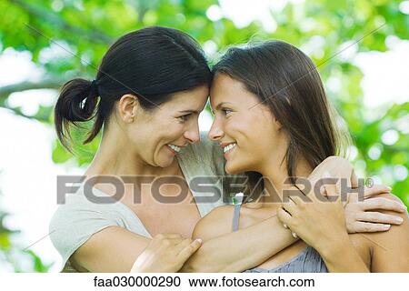 Stock Image - Mother and teen daughter embracing, smiling at each other, touching foreheads. Fotosearch