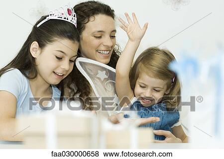 Mother and two daughters playing dress-up, smiling, one girl wearing tiara, the other wearing wings View Large Photo Image Stock Photo - Mother and two daughters playing dress-up, smiling, one girl wearing tiara, the other wearing wings. Fotosearch