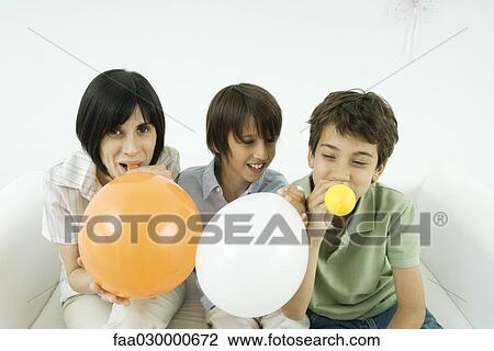 Mother and two sons inflating balloons, smiling, woman looking at camera View Large Photo Image Stock Image - Mother and two sons inflating balloons, smiling, woman looking at camera. Fotosearch