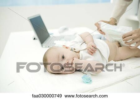 Mother changing baby's diaper on desk, laptop in background View Large Photo Image Stock Photo - Mother changing baby's diaper on desk, laptop in background. Fotosearch