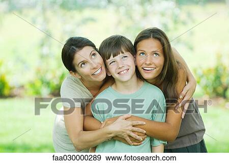 Stock Photo - Mother embracing son and teen daughter, all smiling and looking up. Fotosearch