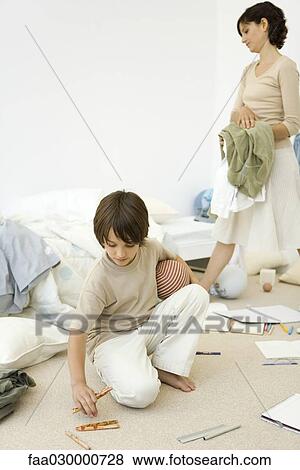 Mother helping boy clean messy room View Large Photo Image Stock Photo - Mother helping boy clean messy room. Fotosearch