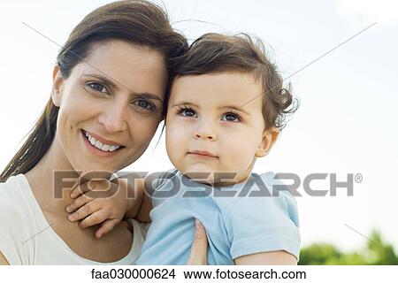 Mother holding baby, smiling at camera, portrait View Large Photo Image Picture - Mother holding baby, smiling at camera, portrait. Fotosearch