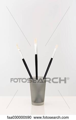 Stock Image - Paint brushes sticking out of cup, close-up. Fotosearch