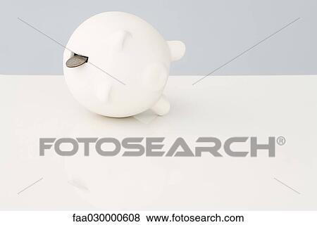 Stock Photo - Piggy bank on its side with a coin falling out. Fotosearch