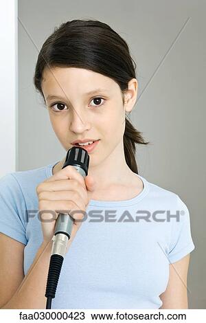 Preteen girl holding microphone, looking at camera, portrait View Large Photo Image Stock Image - Preteen girl holding microphone, looking at camera, portrait. Fotosearch