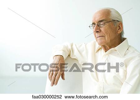 Senior man sitting on couch, eyes closed View Large Photo Image Stock Image - Senior man sitting on couch, eyes closed. Fotosearch