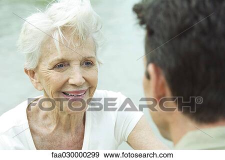 Senior woman smiling at man, over the shoulder view View Large Photo Image Stock Photo - Senior woman smiling at man, over the shoulder view. Fotosearch