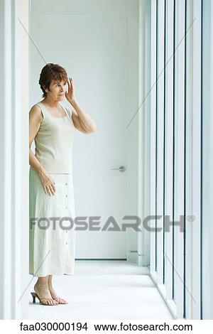 Senior woman standing in hallway, looking toward window View Large Photo Image Picture - Senior woman standing in hallway, looking toward window. Fotosearch