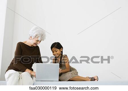 Senior woman using laptop with little girl View Large Photo Image Stock Photo - Senior woman using laptop with little girl. Fotosearch