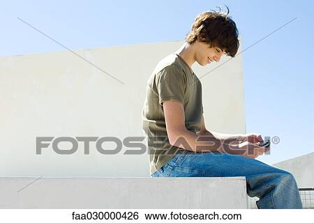Teen boy playing handheld video game outdoors View Large Photo Image Stock Photograph - Teen boy playing handheld video game outdoors. Fotosearch
