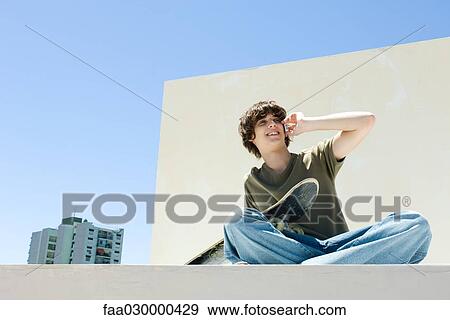 Teen boy using cell phone in urban setting, holding skateboard View Large Photo Image Stock Photo - Teen boy using cell phone in urban setting, holding skateboard. Fotosearch
