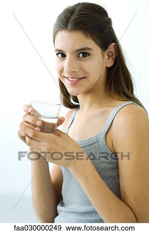 Teen girl holding glass of water, smiling at camera View Large Photo Image Stock Photo - Teen girl holding glass of water, smiling at camera. Fotosearch
