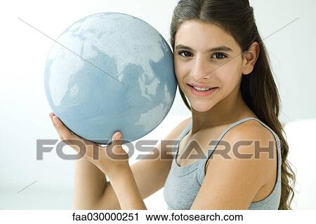 Teen girl holding globe up to face, smiling at camera View Large Photo Image Stock Image - Teen girl holding globe up to face, smiling at camera. Fotosearch