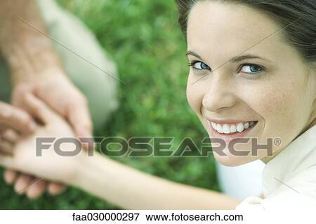 Stock Photo - Teen girl holding man's hand, smiling over shoulder at camera, cropped view. Fotosearch