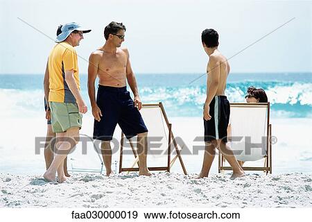 Stock Photo - Three generation family on beach, full length. Fotosearch