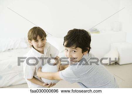 Two boys playing with ball, smiling at camera View Large Photo Image Stock Photograph - Two boys playing with ball, smiling at camera. Fotosearch