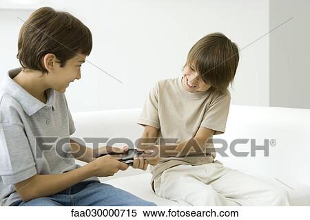 Two brothers fighting over handheld video game View Large Photo Image Stock Photography - Two brothers fighting over handheld video game. Fotosearch