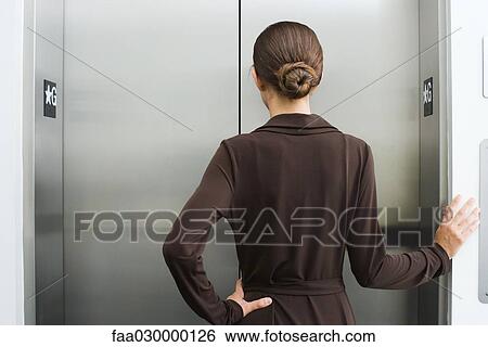 Well-dressed female waiting for elevator, rear view View Large Photo Image Stock Photograph - Well-dressed female waiting for elevator, rear view. Fotosearch