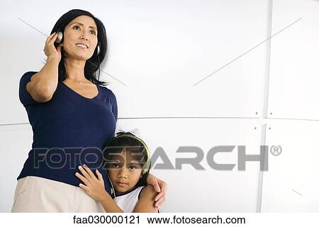 Stock Image - Woman and little girl listening to headphones. Fotosearch