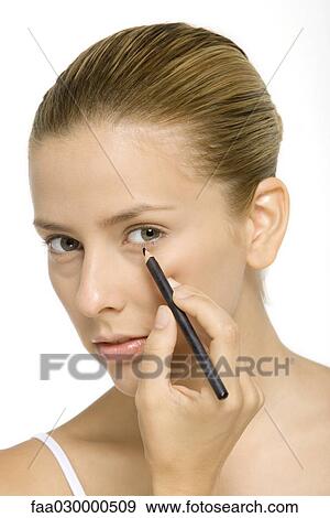 Woman applying eyeliner, looking at camera, close-up View Large Photo Image Stock Photo - Woman applying eyeliner, looking at camera, close-up. Fotosearch