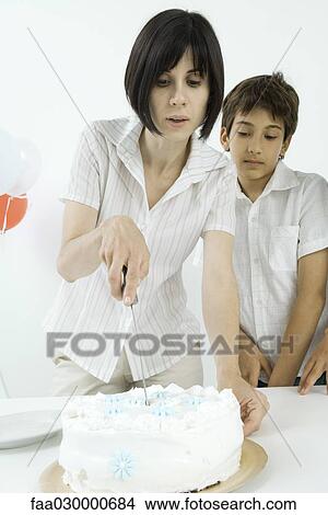 Picture - Woman cutting birthday cake, son watching. Fotosearch
