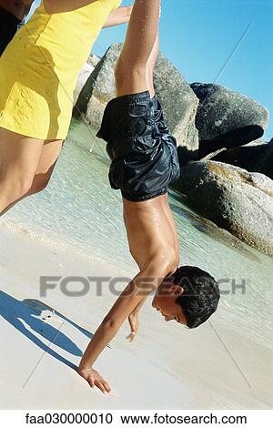 Woman helping boy do handstand on beach View Large Photo Image Stock Image - Woman helping boy do handstand on beach. Fotosearch