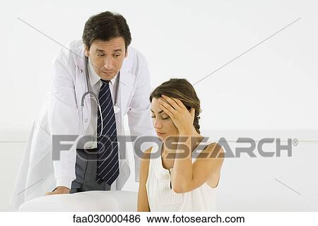 Woman holding head, doctor leaning behind her View Large Photo Image Stock Photograph - Woman holding head, doctor leaning behind her. Fotosearch