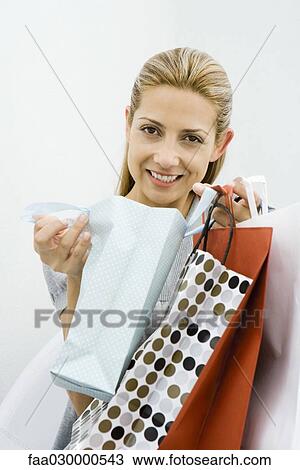 Woman holding several shopping bags, smiling at camera View Large Photo Image Stock Image - Woman holding several shopping bags, smiling at camera. Fotosearch