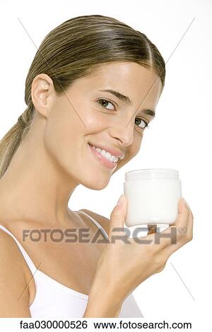 Woman holding up jar of moisturizer, smiling at camera View Large Photo Image Stock Photograph - Woman holding up jar of moisturizer, smiling at camera. Fotosearch