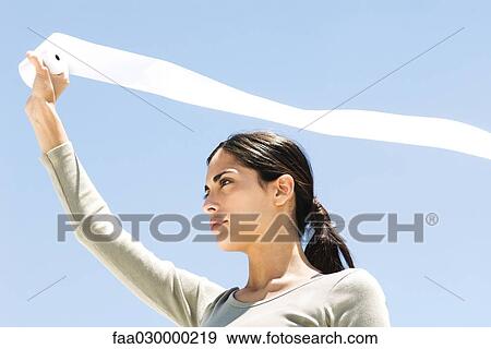 Woman holding up toilet paper roll outdoors, paper streaming in wind, low angle view View Large Photo Image Stock Photo - Woman holding up toilet paper roll outdoors, paper streaming in wind, low angle view. Fotosearch