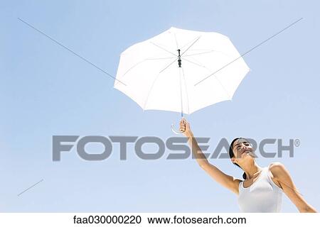 Woman holding up umbrella, low angle view View Large Photo Image Stock Image - Woman holding up umbrella, low angle view. Fotosearch