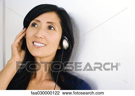 Woman listening to headphones, smiling View Large Photo Image Stock Image - Woman listening to headphones, smiling. Fotosearch