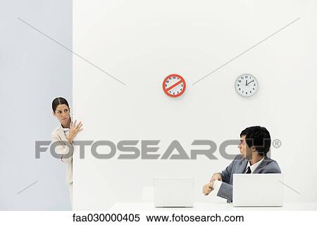 Woman peeking around corner as boss points at wristwatch, clocks on wall in background View Large Photo Image Stock Photography - Woman peeking around corner as boss points at wristwatch, clocks on wall in background. Fotosearch