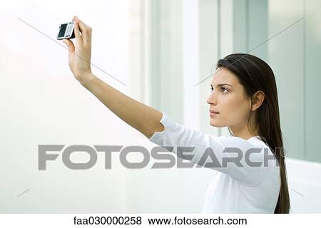 Woman photographing herself with photophone, arm raised View Large Photo Image Stock Photo - Woman photographing herself with photophone, arm raised. Fotosearch