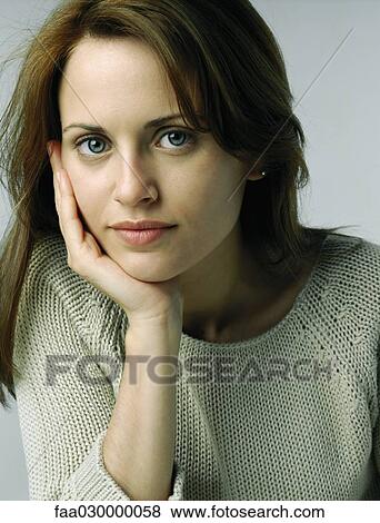 Stock Photo - Woman resting chin in hand, looking at camera, portrait. Fotosearch