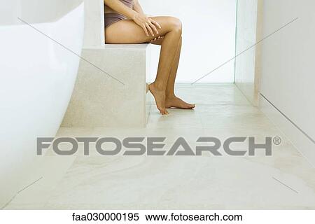 Stock Photography - Woman sitting in bathroom, in underwear, low section. Fotosearch